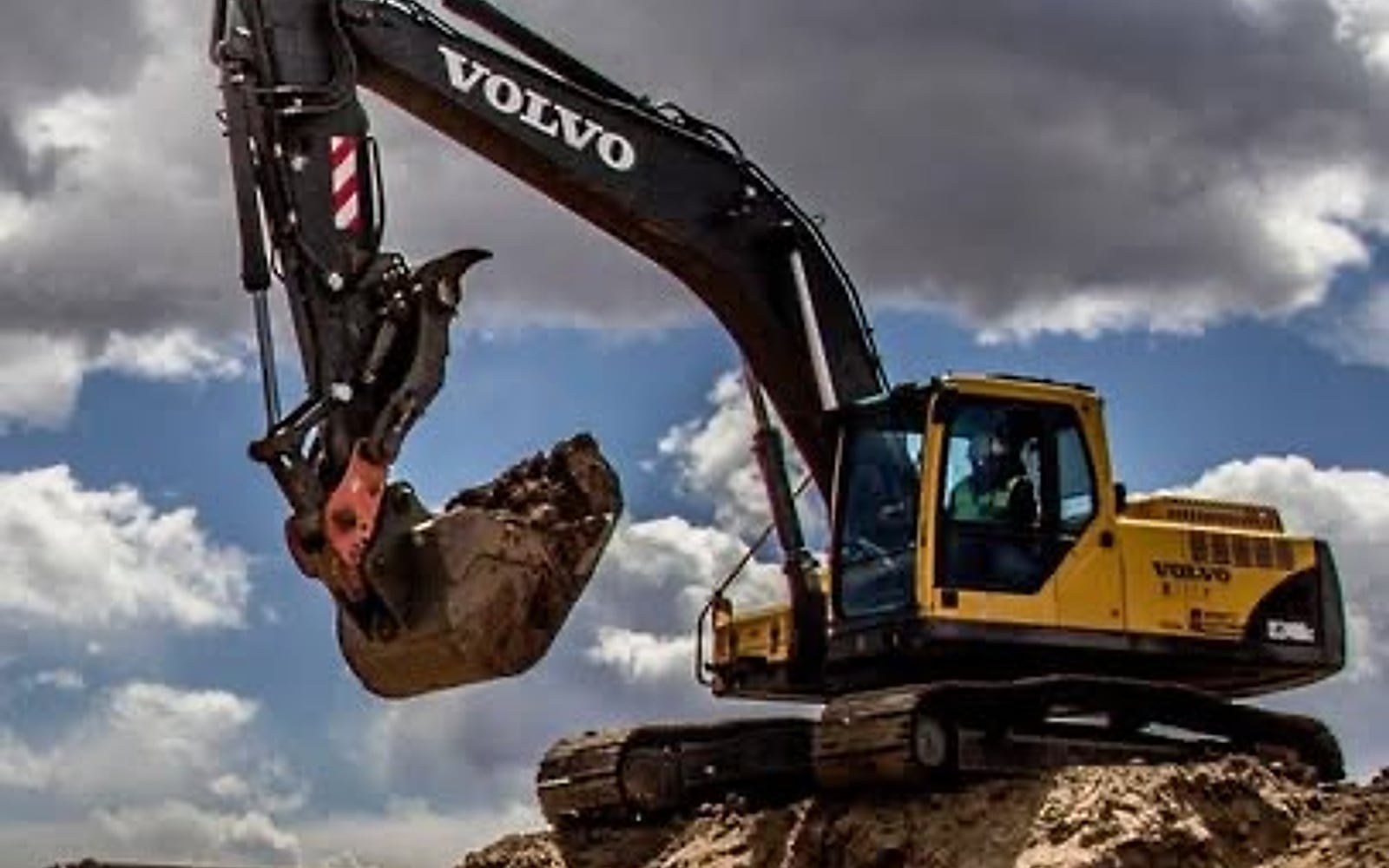 Volvo excavator digging on an Arizona site under dramatic clouds